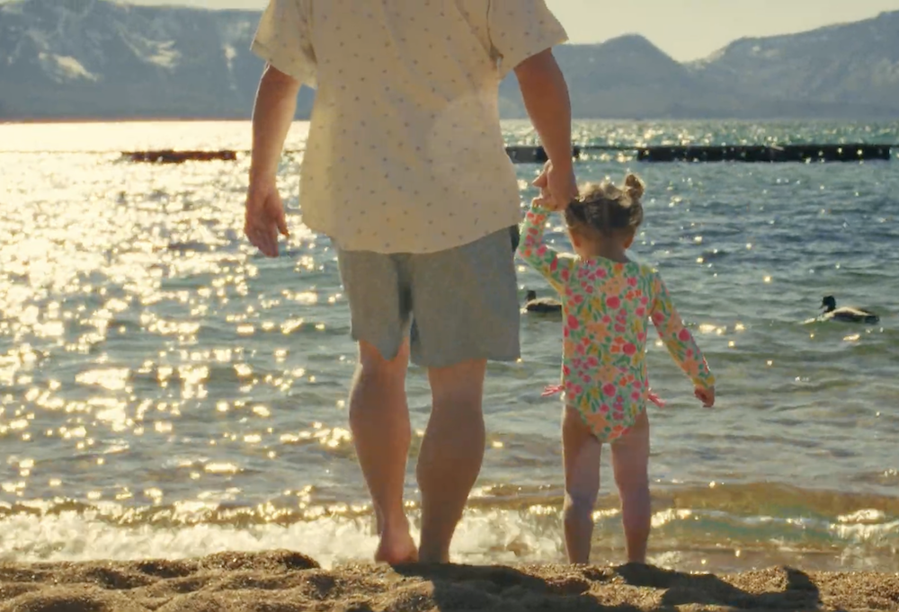 dad and daughter walking into lake tahoe at lakeside beach